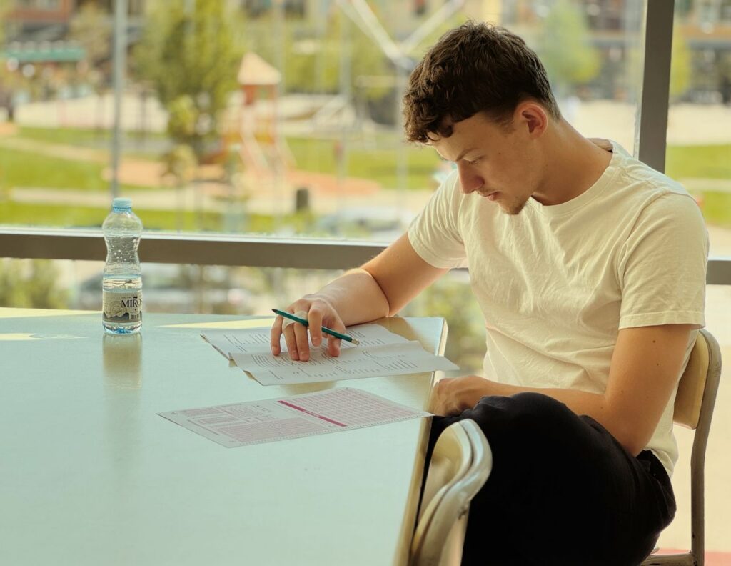 Young man attentively studying in a bright room with paperwork.
