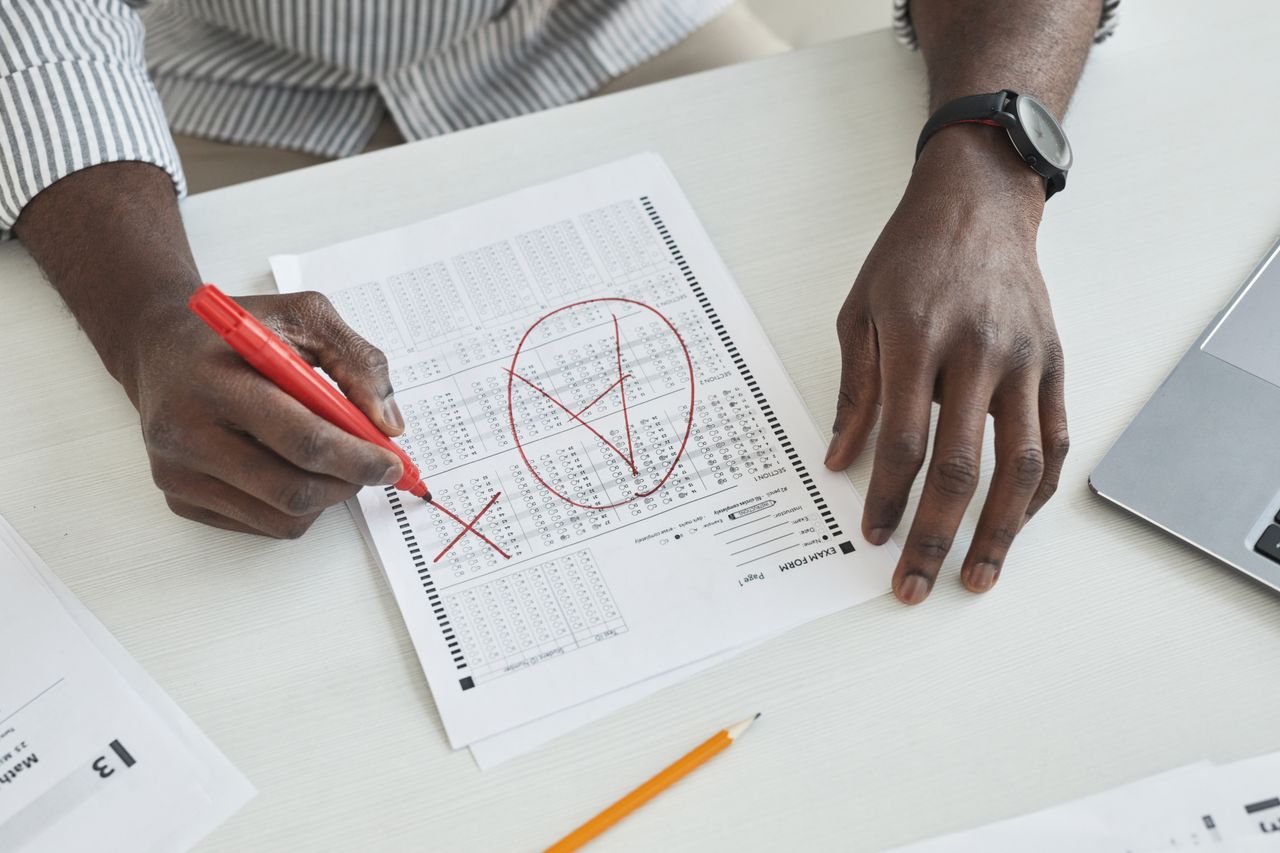 Mastering the First Impression: Your intriguing post title goes here Close-up of a teacher marking a test paper with a red marker on a desk.